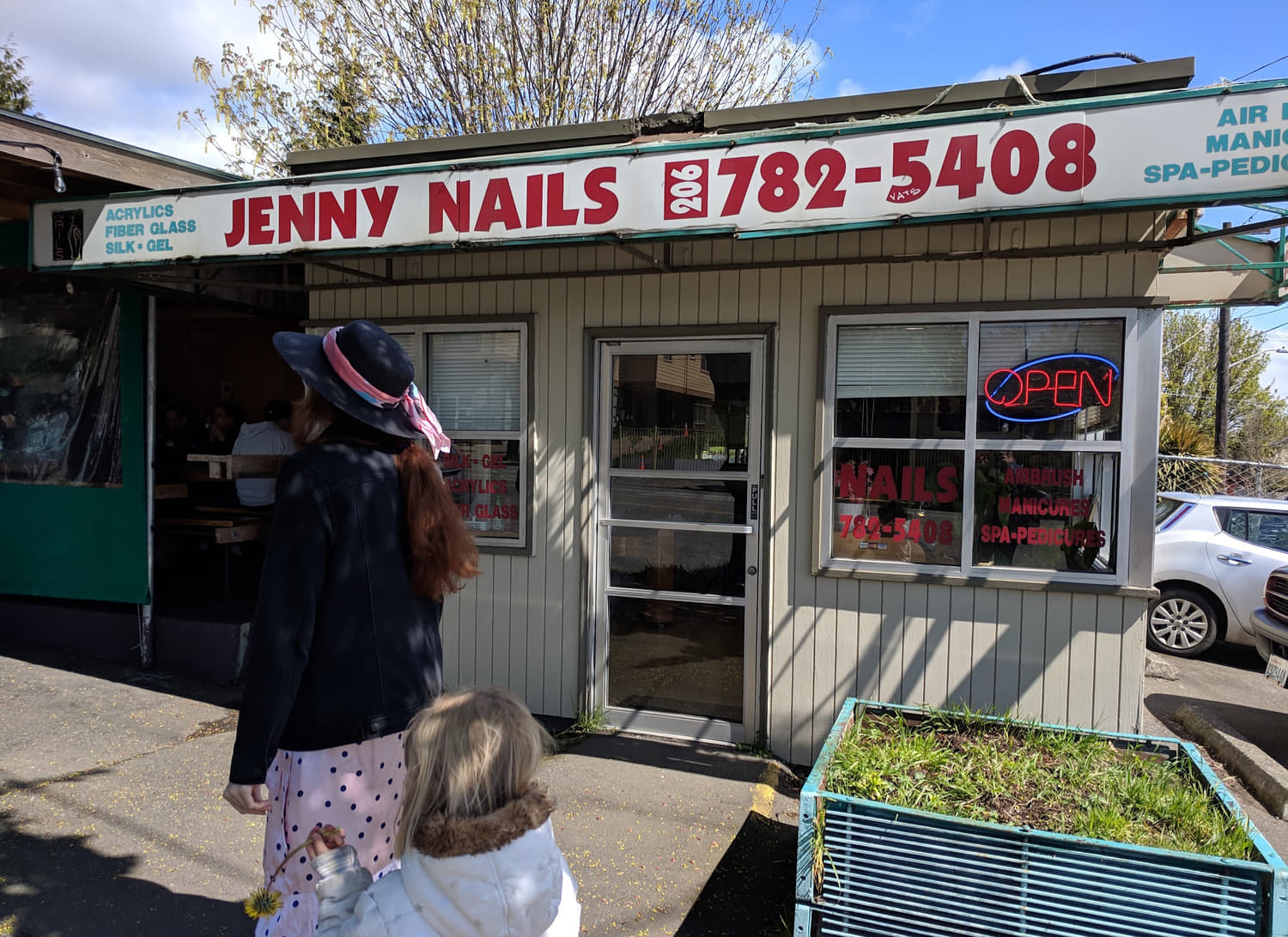 The Jenny Nails storefront on 15th Ave NW: white awning with red lettering and the phone number, green trim and a neon OPEN sign